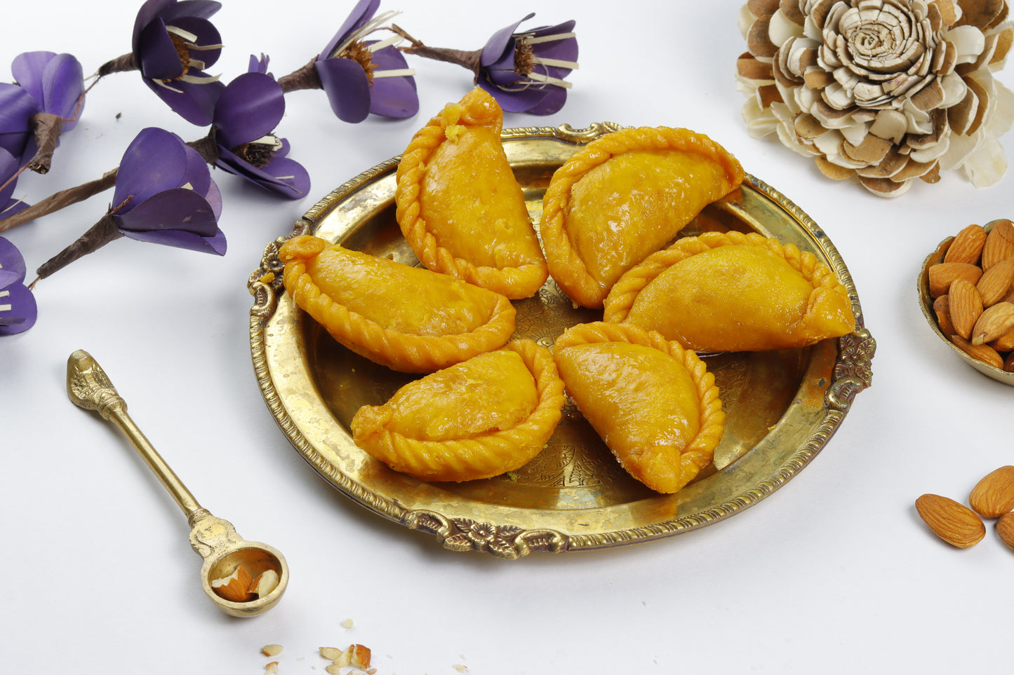 Nutty Ghee Sweets kesar gujiya in Gurgaon saffron gujiya on a brass plate with almonds and decorative flowers