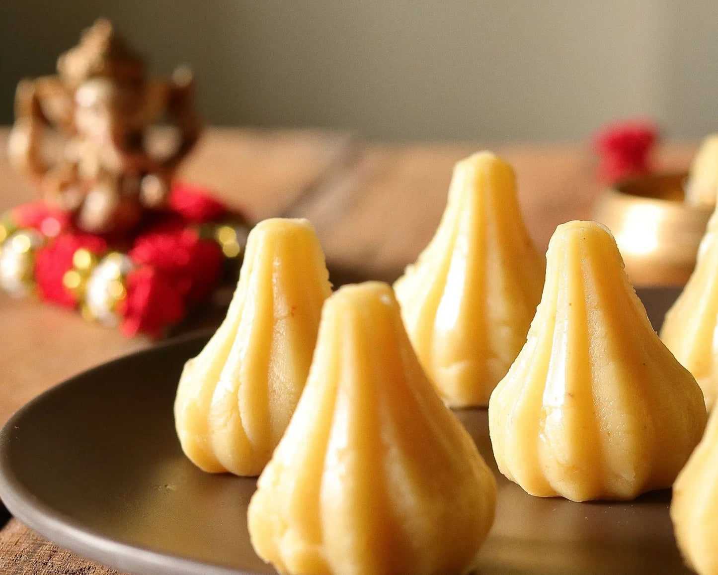 Nutty Ghee Sweets mawa modak in Gurgaon plate of traditional ghee mawa modaks with Ganesh puja background