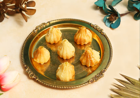 Nutty Ghee Sweets milk cake modak in Gurgaon on a decorative brass plate with seven golden modaks