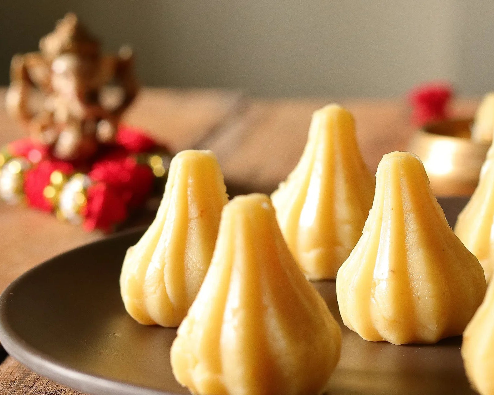 Nutty Ghee Sweets mawa modak in Gurgaon plate of traditional ghee mawa modaks with Ganesh puja background