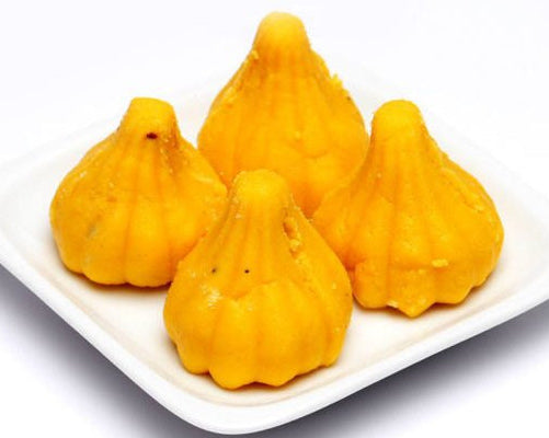 Nutty Ghee Sweets kesar mawa modak online Gurgaon four saffron mawa modaks on white plate for festive offering